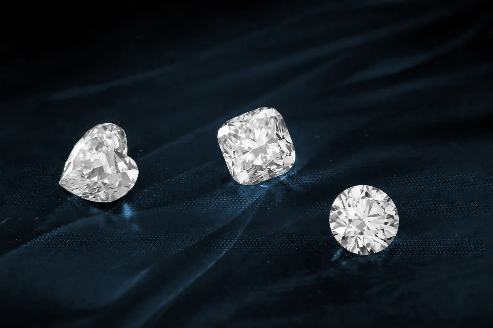 Three gemstones of different shapes on a dark surface