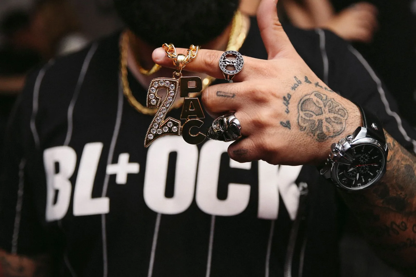 A hand with rings, a watch and a stone-set pendant