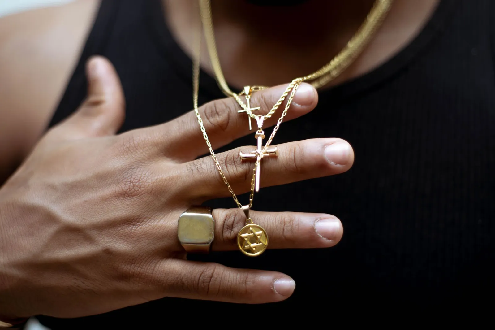 A man’s hand with gold rings and gold chains