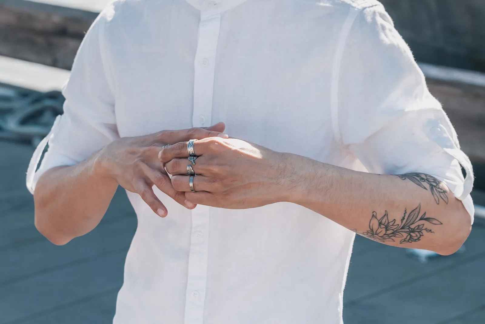 Hands wearing rings against a white shirt