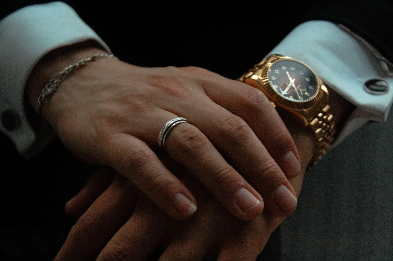 A man’s hands with a ring, a bracelet and a gold watch