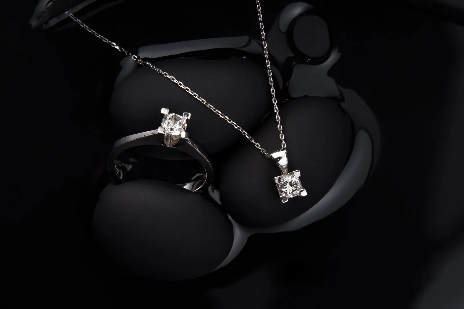 A white-metal ring and pendant on a black background