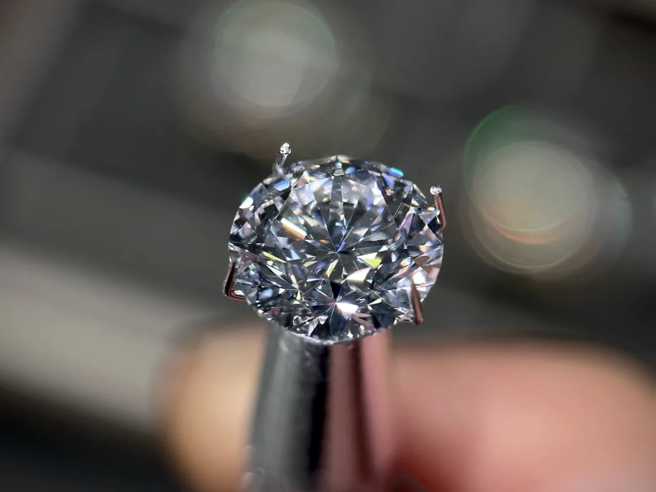 A gemstone held in tweezers for inspection