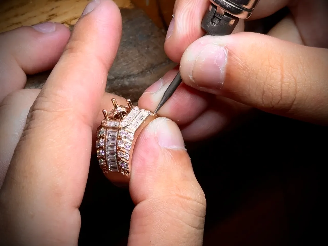 A craftsman setting gemstones into a ring with a hand tool